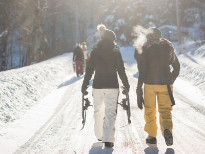 白天在雪山上行走时手持雪地滑雪板的人
